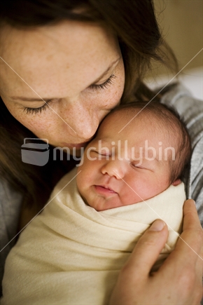 A mother holds her new born baby wrapped in swaddling