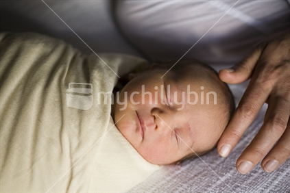 A mother caresses her new born baby wrapped in swaddling