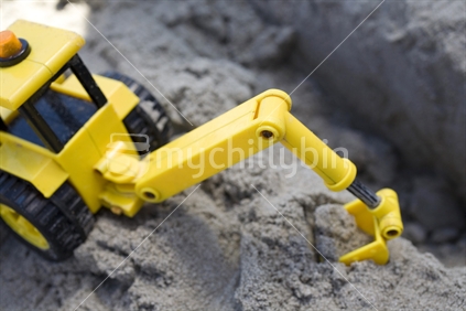 A yellow plastic digger in the sand