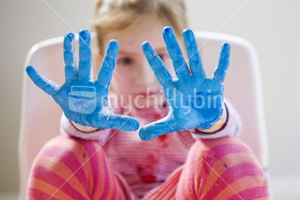 Young girl with blue painted hands outstretched