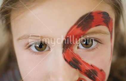 Close of young girl with hazel eyes and a snake painted on her face