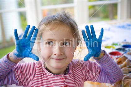 A young girl with blue painted outstretched hands