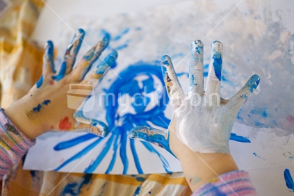 A young girls hands covered in paint