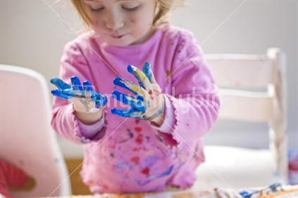 A young girls hands covered in paint