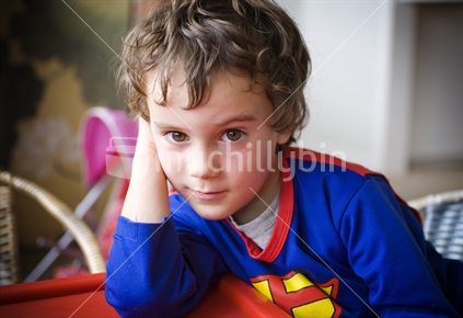 A young contemplative boy in a superman top