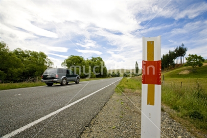 Car driving on an open country road past road markers