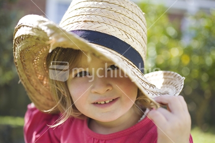 A young girl in a large straw hat having fun
