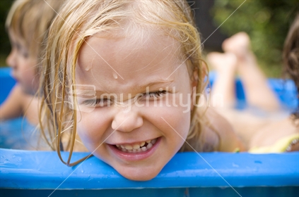 A young girl laughing in a paddling pool
