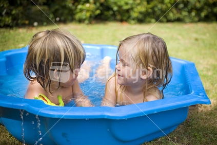 2 blonde kids playing in a paddling pool