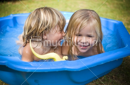 2 blonde kids playing in a paddling pool