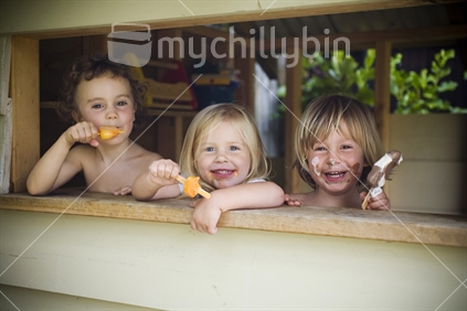 3 kids eating ice cream and leaning out the window of a playhut