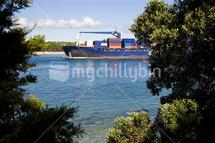 A container ship heading into the Tauranga Harbou past Mount Maunganui