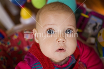 A young happy baby looking up at the camera with large eyes