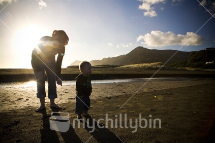 Silhouette of a mother & child on Piha beach, Auckland, New Zealand