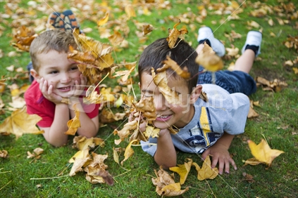 2 brothers playing in autumn leaves