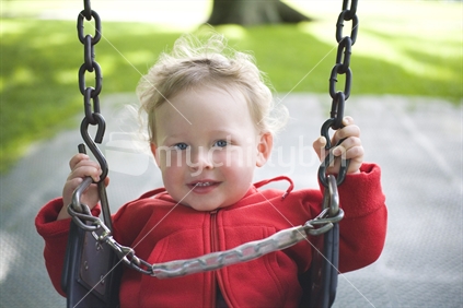 A young blonde boy on a playground swing