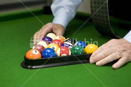 Setting up the balls in a plastic triangle for a game of pool