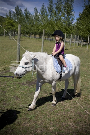 A young girl enjoying a summer pony ride 