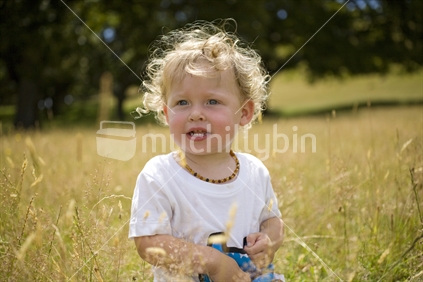 A young blonde boy in a field of long late summer grass