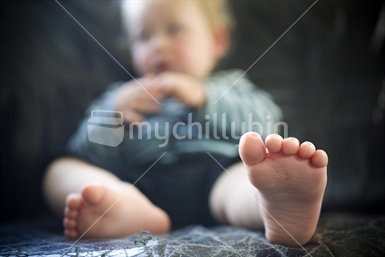 Closeup of feet of young boy sitting on an old leather couch, New Zealand