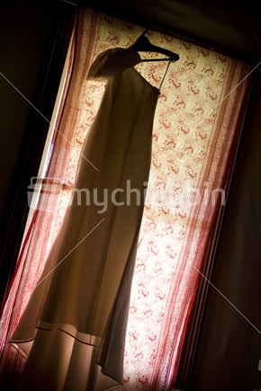 A wedding dress silhouetted against a window