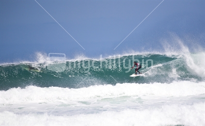 Surfer catching a wave at Piha Beach