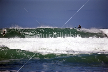 Surfer catching a wave at Piha Beach
