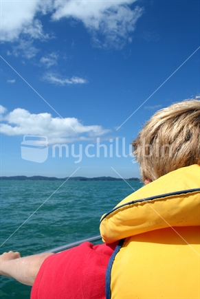 A young boy wearing a lifejacket at sea