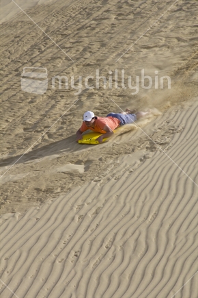 A tourist sand boarding at Te Paki dunes in Northland.