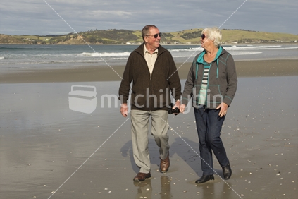 Retired couple walking the beach.