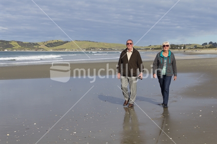 Older adult couple strolling Omaha beach. 