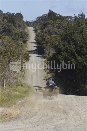 A man drives his quad bike and trailer with small boat on the back, dirt road Northland.