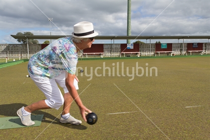 Older woman playing lawn bowls on club green