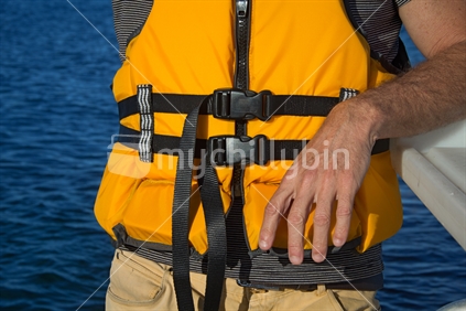 A man wears a yellow life jacket while boating.