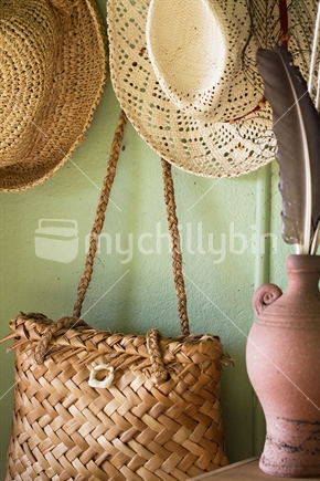 Woven hats and flax kete bag against green backdrop. 