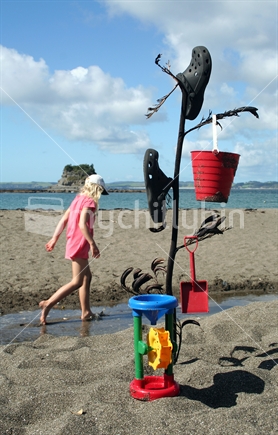 Abandoned beach toys with girl in the background, Mathesons Bay, New Zealand