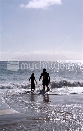 Father and son play in the shallow surf