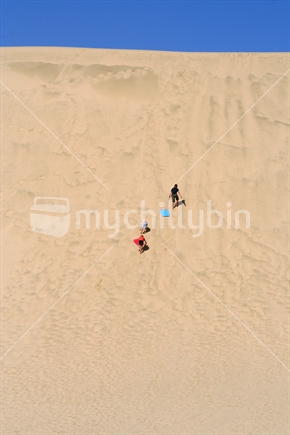 Three children are dwarfed by the giant sand dunes of Te Paki, New Zealand