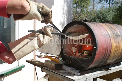Pulling fired pottery out of a Raku Kiln