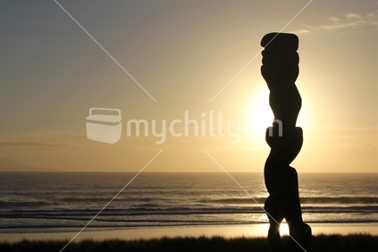 Carving of Matariki stands guardian of Omaha Beach, Rodney, New Zealand  - landscape format.