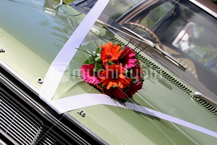 Classic car with wedding bouquet on bonnet.