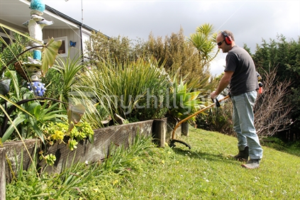 Man in garden using a line trimmer to cut borders.