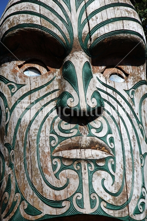 Wooden Maori carving, details of a Pou standing at Omaha beach, New Zealand.