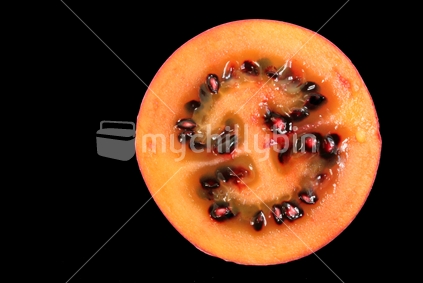 Slice of Tamarillo with black background and copy space. 