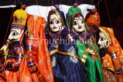 Colourful Indian puppets hanging up in a market place stall at the Kowhai festival, Warkworth.
