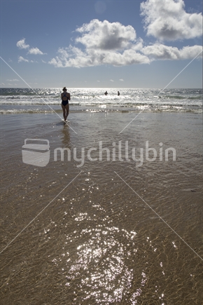 Teenage girl walking towards the ocean to go for a swim. 