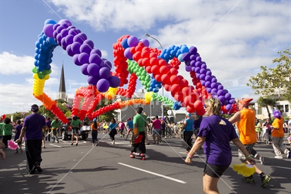String of rainbow balloons (symbol of gay pride) encircling a church spire.