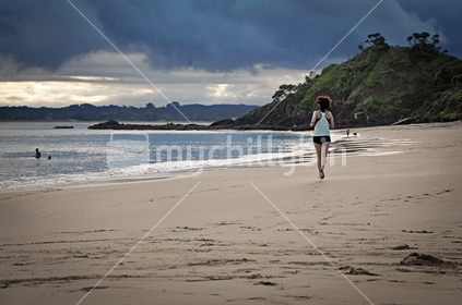Woman goes for an evening run on the beach (selective focus, low light image)