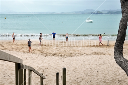 Family plays beach cricket (selective focus and some motion blur)