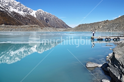 People standing at the edge of the Tasman Glacier lake jetty